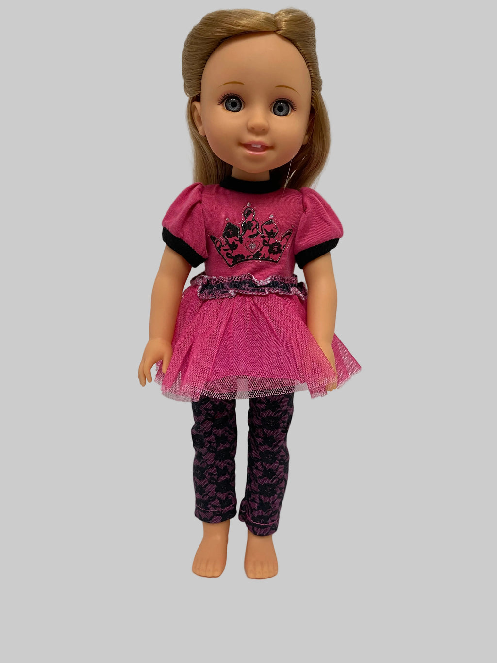 A doll with blonde hair wearing a pink and black dress with patterned tights, shown against a plain gray background.